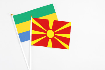 Macedonia and Gabon stick flags on white background. High quality fabric, miniature national flag. Peaceful global concept.White floor for copy space.