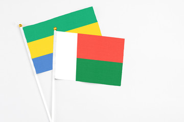Madagascar and Gabon stick flags on white background. High quality fabric, miniature national flag....