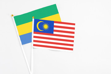 Malaysia and Gabon stick flags on white background. High quality fabric, miniature national flag. Peaceful global concept.White floor for copy space.