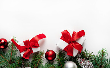 Christmas composition on a white background with white gift boxes, with a red ribbon with fir branches, toys, copy space for your congratulations