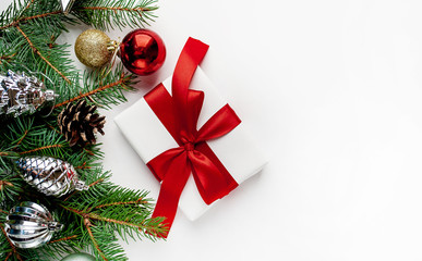 Christmas composition on a white background with white gift boxes, with a red ribbon with fir branches, toys, copy space for your congratulations