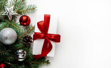 Christmas composition on a white background with white gift boxes, with a red ribbon with fir branches, toys, copy space for your congratulations