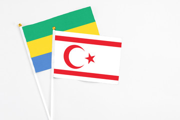 Northern Cyprus and Gabon stick flags on white background. High quality fabric, miniature national flag. Peaceful global concept.White floor for copy space.