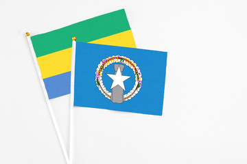 Northern Mariana Islands and Gabon stick flags on white background. High quality fabric, miniature national flag. Peaceful global concept.White floor for copy space.