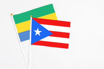 Puerto Rico and Gabon stick flags on white background. High quality fabric, miniature national flag. Peaceful global concept.White floor for copy space.