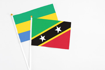 Saint Kitts And Nevis and Gabon stick flags on white background. High quality fabric, miniature national flag. Peaceful global concept.White floor for copy space.