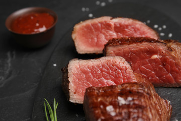 Delicious sliced beef tenderloin on black table, closeup