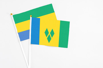 Saint Vincent And The Grenadines and Gabon stick flags on white background. High quality fabric, miniature national flag. Peaceful global concept.White floor for copy space.