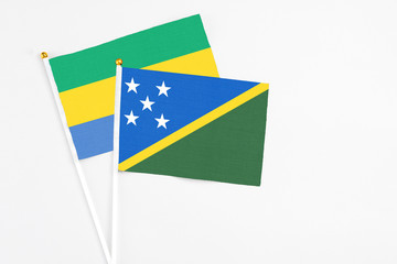 Solomon Islands and Gabon stick flags on white background. High quality fabric, miniature national...