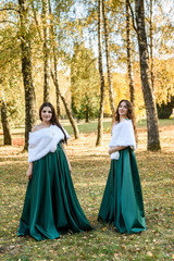 Fototapeta premium Ladies in elegant green dresses walking in autumn park. Brunette girl Dreamy young girls laughing on the outdoors