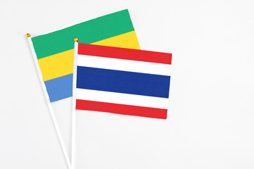 Thailand and Gabon stick flags on white background. High quality fabric, miniature national flag. Peaceful global concept.White floor for copy space.