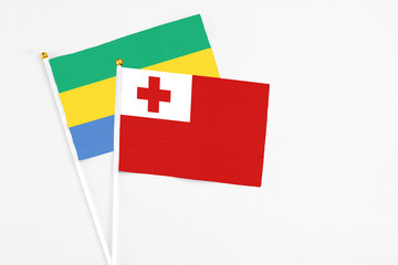 Tonga and Gabon stick flags on white background. High quality fabric, miniature national flag. Peaceful global concept.White floor for copy space.