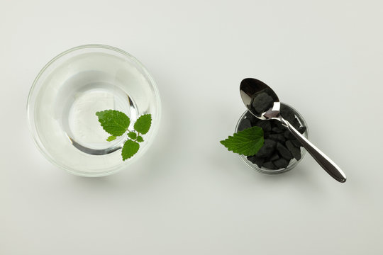 Purification of drinking water with shungite stones, transparent bowls with stones and water on a white background. Removing toxins and organic substances from the water.