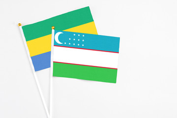 Uzbekistan and Gabon stick flags on white background. High quality fabric, miniature national flag....