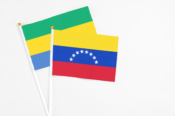 Venezuela and Gabon stick flags on white background. High quality fabric, miniature national flag. Peaceful global concept.White floor for copy space.