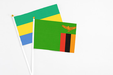 Zambia and Gabon stick flags on white background. High quality fabric, miniature national flag. Peaceful global concept.White floor for copy space.