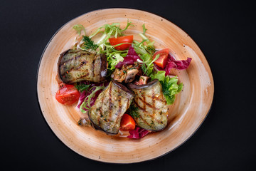 Top view. Restaurant food. Grilled eggplant rolls with fried champignons, garlic feta, tomato and herbs. Baked Vegetables and Cottage Cheese Close Up. Vegetarian dish.