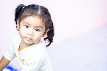 A little girl with a smiling face, two and a half years old, wearing a white shirt