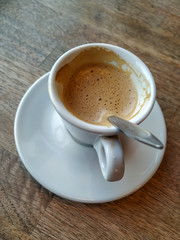 Espresso with latte in a white cup and plate served on wooden table on a break with fresh and warm beverage