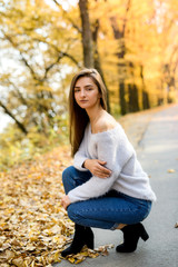 Autumn landscape. Woman in casual wear posing in park with yellow leaves