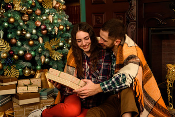 Young couple with gifts near Christmas tree