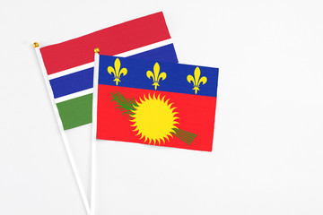 Guadeloupe and Georgia stick flags on white background. High quality fabric, miniature national flag. Peaceful global concept.White floor for copy space.
