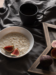 porridge with figs on coconut milk on a gray background and a wooden stand. Ingredients for a healthy breakfast.