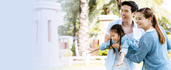 Asian family has a father, mother, and daughter smiling happy in the park during the summer holidays. Everyone wear blue shirts. Embracing each other demonstrates love, care for the health of family.