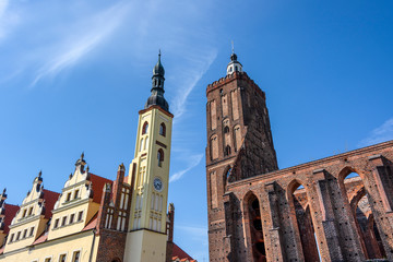 Poland, Guben, Gubin: Tower of old city hall and ruin of historic Parish church from below in the city center of the small town near German Polish border with blue sky in the background - travel.