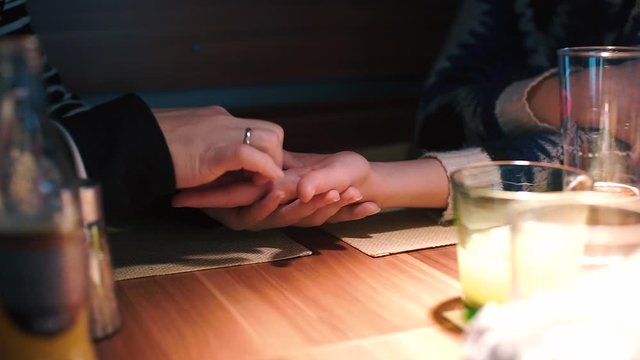 Woman divines on the hand of a lesbian friend at a table in a restaurant.