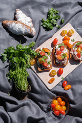 toasts with ham and tomatoes, croissants and greens on a gray background. 