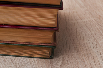 A stack of old books of different colors on a beige background. Yellow faded pages of the book, crumpled corners, of different size.
