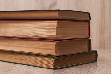 A stack of old books of different colors on a beige background. Yellow faded pages of the book, crumpled corners, of different size.
