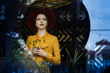 girl in a cafe with a cup of coffee and a hat.portrait of sensual young girl wearing floppy hat and...