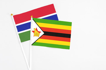 Zimbabwe and Georgia stick flags on white background. High quality fabric, miniature national flag. Peaceful global concept.White floor for copy space.