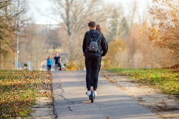Fototapeta premium A guy and a girl rides an electric scooter in the autumn Park