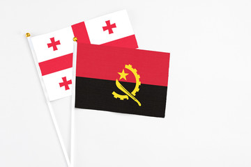 Angola and Georgia stick flags on white background. High quality fabric, miniature national flag. Peaceful global concept.White floor for copy space.