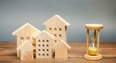 Miniature wooden houses and hourglass. Mortgage and loan concept. Temporary rental housing. Real...