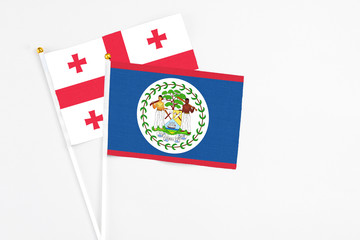 Belize and Georgia stick flags on white background. High quality fabric, miniature national flag. Peaceful global concept.White floor for copy space.