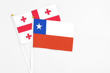 Chile and Georgia stick flags on white background. High quality fabric, miniature national flag. Peaceful global concept.White floor for copy space.