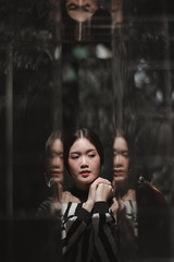 Fototapeta na wymiar street portrait, strong woman in black, confident woman, lady in city, portrait of Asian female, close up, reflection face, young lady in black white stripe top