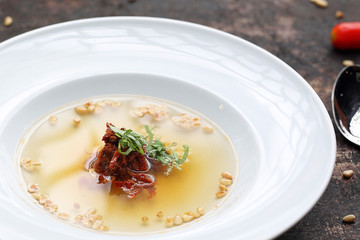Consome, aromatic transparent tomato soup with the addition of dried tomatoes and roasted pine nuts.