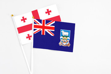 Fototapeta premium Falkland Islands and Georgia stick flags on white background. High quality fabric, miniature national flag. Peaceful global concept.White floor for copy space.