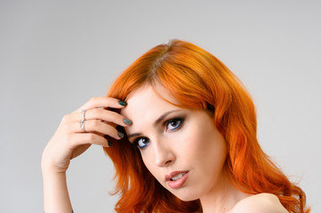 Close-up portrait of a red-haired pretty girl with excellent makeup and bright curly hair on a white background. Beauty concept, sample of beautiful hairstyle and makeup with cosmetics.