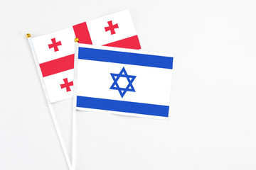 Israel and Georgia stick flags on white background. High quality fabric, miniature national flag. Peaceful global concept.White floor for copy space.