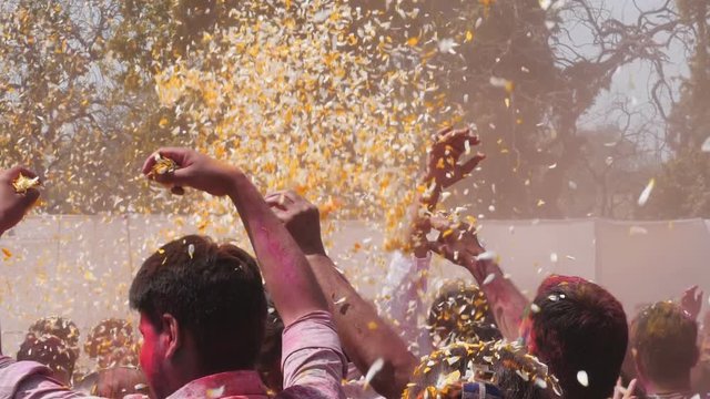 slow motion clip of petals being thrown into the air above a crowd during holi celebrations in jaipur, india