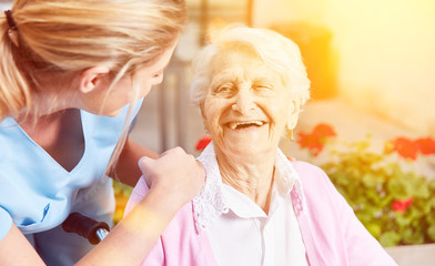 Lachende Seniorin mit Pflegekraft im Altersheim