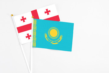 Kazakhstan and Georgia stick flags on white background. High quality fabric, miniature national flag. Peaceful global concept.White floor for copy space.