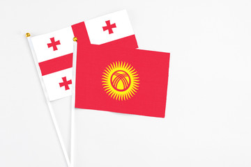 Kyrgyzstan and Georgia stick flags on white background. High quality fabric, miniature national flag. Peaceful global concept.White floor for copy space.