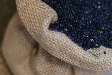 Black sesame seeds in sack as background